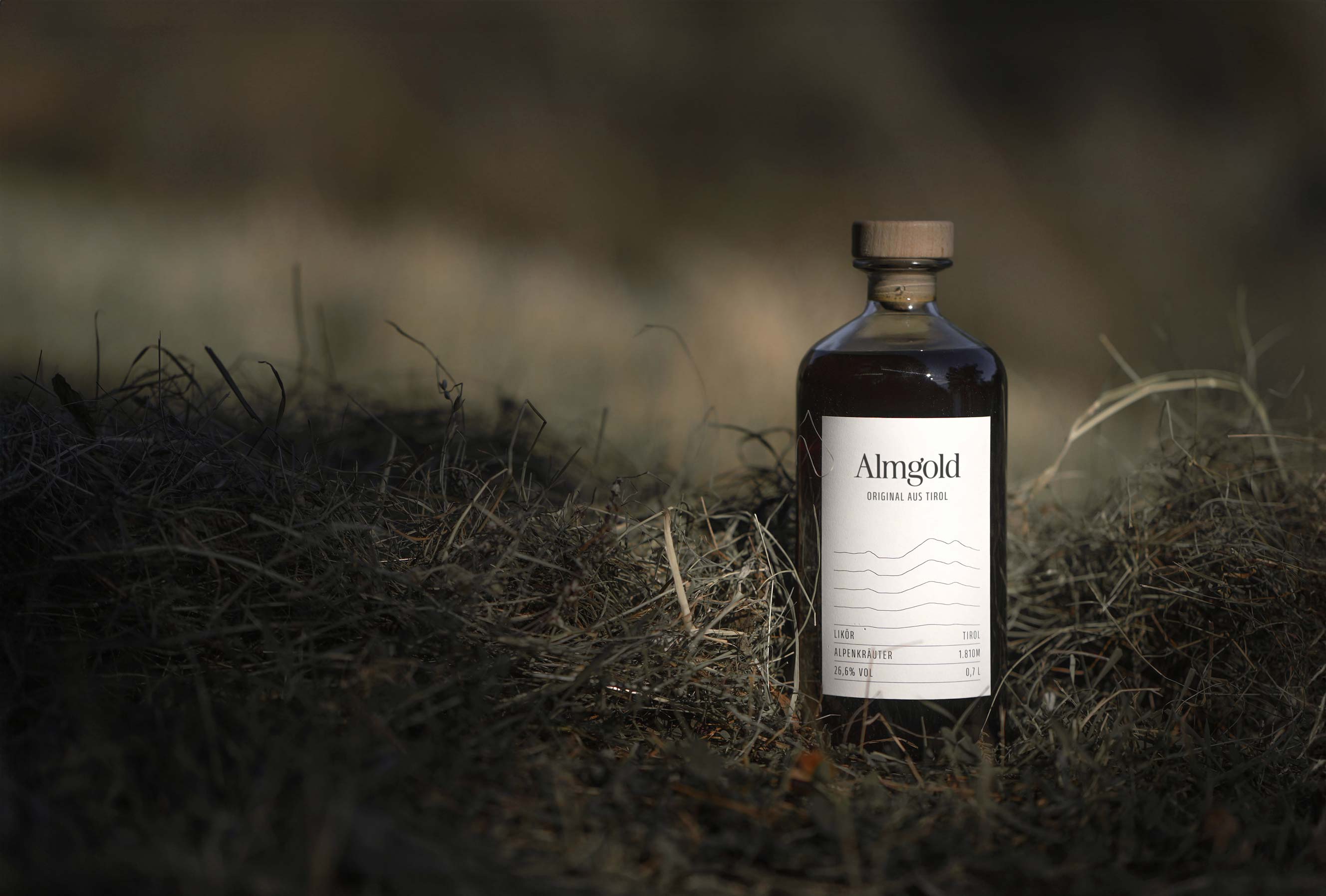 Almgold Flasche mit Heu im Hintergrund